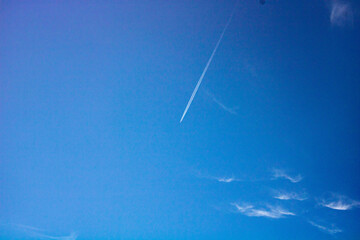 A plane flies high in the clear blue sky.