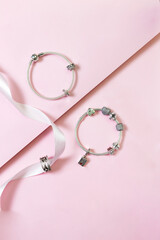 Lady's jewelry charm bracelets on pink background
