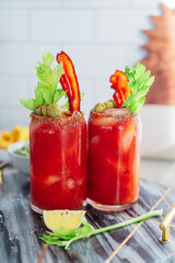 Bloody Mary cocktail with bacon, celery and olives. Chilled brunch and breakfast alcohol drink. Red, green colors. Iced cocktail. Appetizer weekend party.