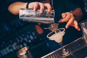 Bartender pouring using strainer White healthy Cocktail drink on a bar counter . Professional view . Trendy stylish alcoholic drink .  Design people and luxury concept service barman in nightclub