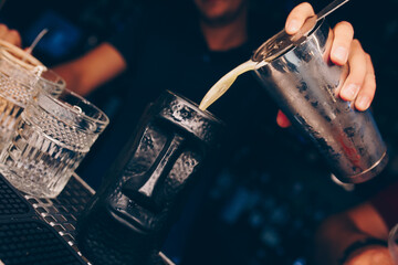 Bartender pouring using strainer White healthy Cocktail drink on a bar counter . Professional view . Trendy stylish alcoholic drink .  Design people and luxury concept service barman in nightclub