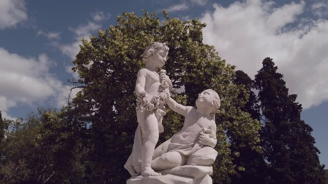 A marble statue with two kids in a garden.