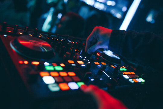 producer  DJ mixer in a nightclub with glowing plays musical rave Dubstep Electronic Trance composition with modern midi controller device in nightclub Live.Musical production process for artists.