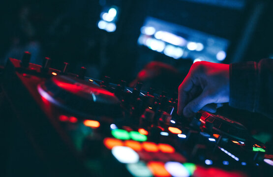 producer  DJ mixer in a nightclub with glowing plays musical rave Dubstep Electronic Trance composition with modern midi controller device in nightclub Live.Musical production process for artists.