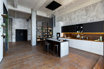 luxury studio apartment with a free layout in a loft style in dark colors. Stylish modern kitchen area with an island, cozy bedroom area with fireplace and personal gym