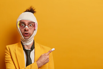 Stunned emotional young European guy had serious accident, has shiner under eye, wears bandage...