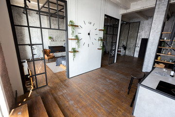 luxury studio apartment with a free layout in a loft style in dark colors. Stylish modern kitchen area with an island, cozy bedroom area with fireplace and personal gym