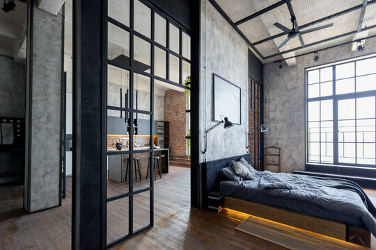 luxury studio apartment with a free layout in a loft style in dark colors. Stylish modern kitchen area with an island, cozy bedroom area with fireplace and personal gym