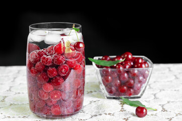 Cherry drink with ice in a jar, on a black background. Selective focus