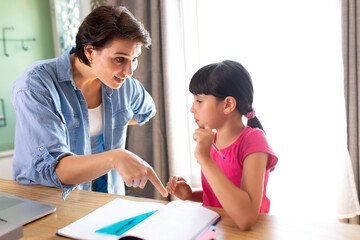 a mother explaining a lesson to her daughter who is working on her school homework