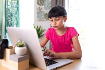 concentrated girl at home who works on a computer like a grown-up