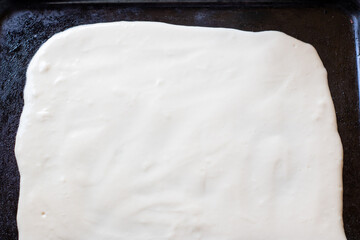 Dough for homemade pizza on a baking sheet