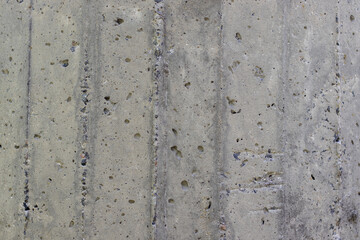 Wall of old ribbed gray concrete with splashes and shells.