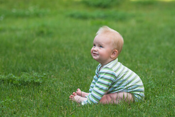 cute little baby sitting on the green grass and looking upwards, banner copy space