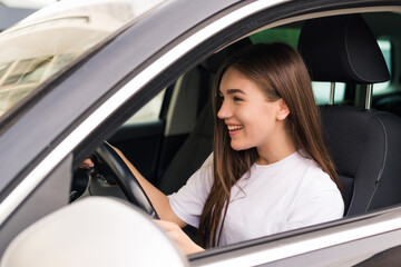 Fototapeta na wymiar Young beautiful smiling girl driving a car on the road