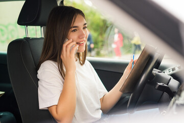 Young woman driving the car and talking on the phone