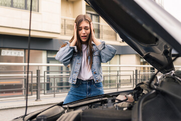 Young woman waits for assistance near her car broken down on the road side.