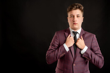 Law student with blond hair dressed in burgundy jacket, white shirt and black tie arranges his jacket