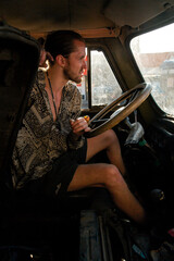 Young cute hippie guy with bun hairstyle and discontented facial expression sitting at the hand...