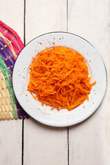 Mexican grated carrot with lime and chili powder on white background