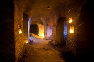 Dark abandoned underground chalky cave temple illuminated by candles