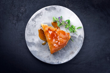 Traditioneller französischer Tarte Tatin Kuchen mit Apfel und Vanille angeboten als Draufsicht auf einem Modern Design Teller mit rustikalen Hintergrund mit Textfreiraum