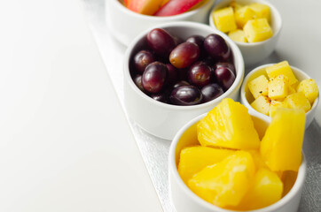 Various set fruits, pineapple, apple, grapes with matured cheddar cheese in bowls