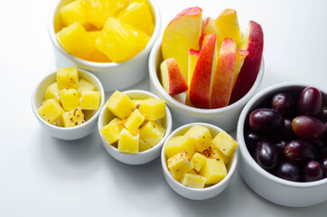 Various set fruits, pineapple, apple, grapes with matured cheddar cheese in bowls