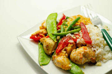 Chicken breast pieces in a Thai red curry sauce made with coconut cream, red chillies, lemongrass, lime leaf, with fragrant rice, red peppers, mange tout, and green beans