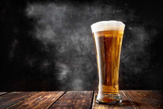 Glass beer on wood table against black background