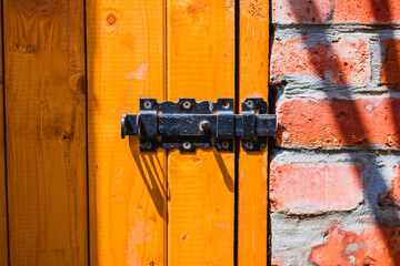 Old vintage iron lock on wooden yellow door on red brick wall background