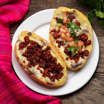 Mexican molletes with chorizo and fresh sauce on wooden background