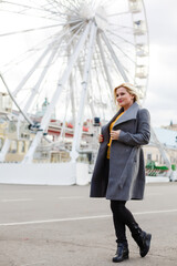 The young girl walks around the city near sights. Ferris wheel. Amusement park. autumn