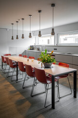  long dining table with red chairs in an office building.