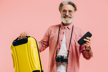 Happy bearded stylish man in sunglasses with camera holding a suitcase and a portable speaker