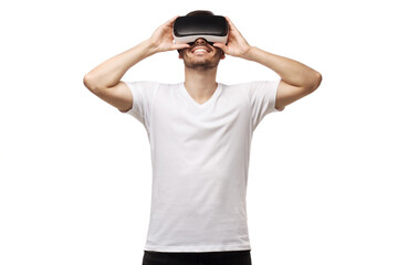 Smiling man wearing tshirt, holding virtual reality headset or VR glasses with both hands, playing video game, isolated on white background