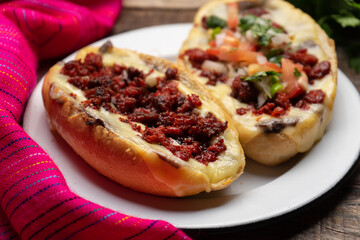 Mexican molletes with chorizo and fresh sauce on wooden background