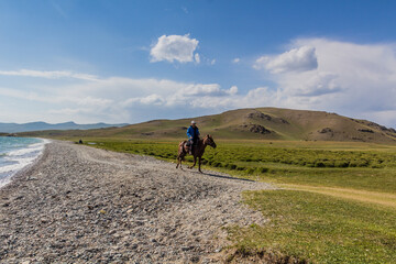 SONG KUL, KYRGYZSTAN - JULY 23, 2018: Horse rider near Song Kul lake, Kyrgyzstan