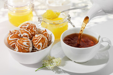 A Cup of hot black tea with cookies and honey on a white background, the filling process . Selective focus
