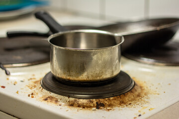 A saucepan and a pan on the dirty white stove.