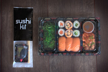 Sushi tray to go with chopsticks kit, soy sauce and wasabi.Nigiri. Maki. Sashimi. Salmon. Tuna. Soy. Wakame. Take-away food concept.
