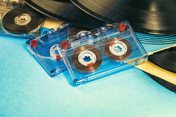 Concept of retro music. Vinyl records and cassette tapes on blue background.