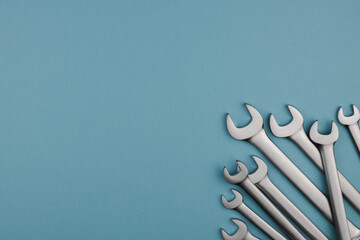 Set chrome spanner keys lying side by side on blue background. Flat lay, top view, minimal composition with copy space