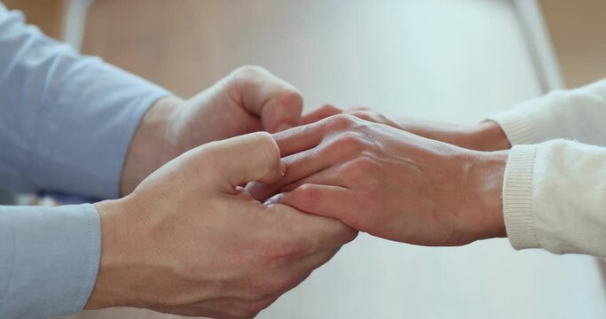 Close up affectionate young man holding hands of beloved woman, showing love and care. Worriend compassionate millennial husband giving psychological help to unhappy wife, solving problems together.
