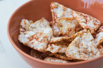 Healthy appetizer - tomato flavor rice chips in orange bowl. Trend of healthy crispy snacks.