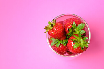 Strawberries are juicy in a bowl. On a pink background.