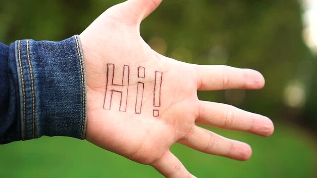Woman shows palm with the inscription on the palm "HI"