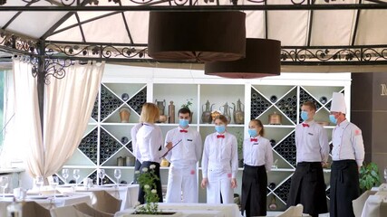 Employees of a restaurant in protective masks after quarantine. Interaction with restaurant manager and his staff on the terrace