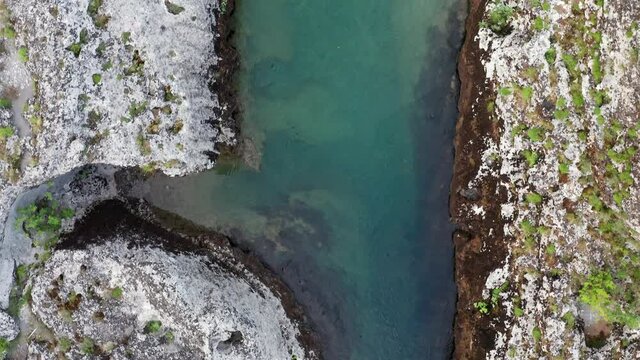 Water flowing into the river. Stream bed cut deep into rock. Fork of a green narrow mountain river flowing through rocky landscape. Upstream of Cijevna (Cem) in Montenegro. Top view aerial footage.