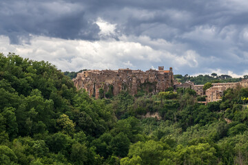 Fototapeta na wymiar Calcata, small medieval village, Italy. Panoramic view of the village of Calcata, in the province of Viterbo, Italy. Medieval village built entirely of tuff and immersed in the green of the forest.